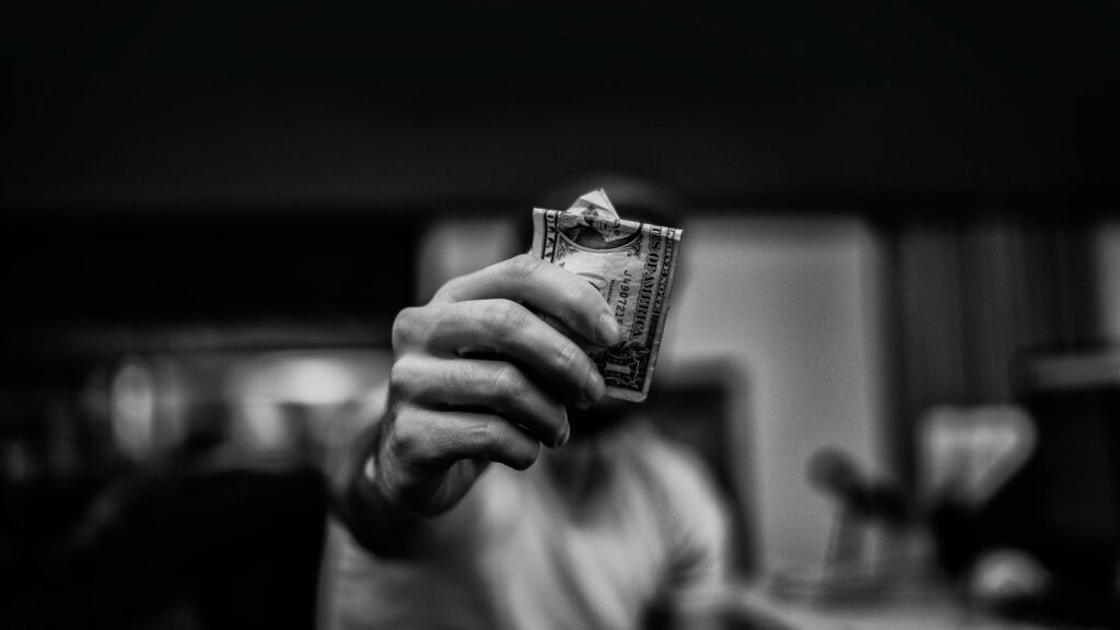 man holding a dollar bill - How Much Money Do You Need to Start Trading Stocks